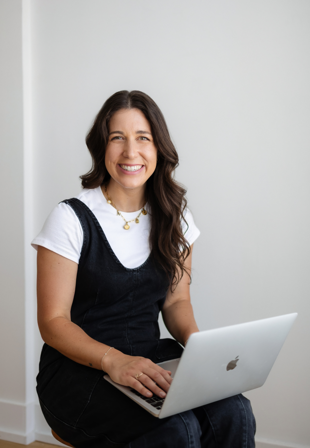 woman sitting on edge of couch, smiling (Rosalie Kassen, sleep consultant vancouver)